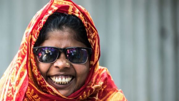 En kvinne met blindhet smiler mot kamera.