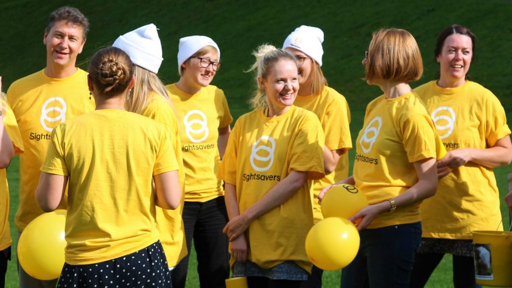 Mennesker med Sightsavers t-skjorter på smilende mot kamera.