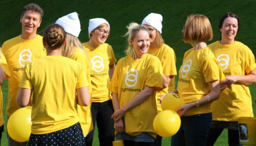 Mennesker med Sightsavers t-skjorter på smilende mot kamera.