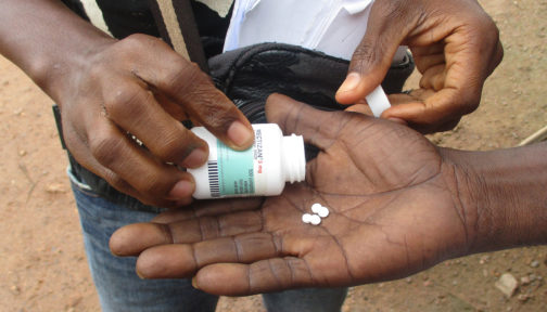 En frivillig plasserer medisiner i en manns utstrakte hånd.