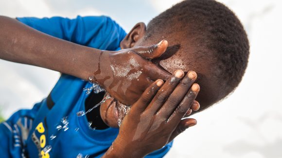 En gutt vasker hendene for å forhindre spredningen av trakominfeksjon.