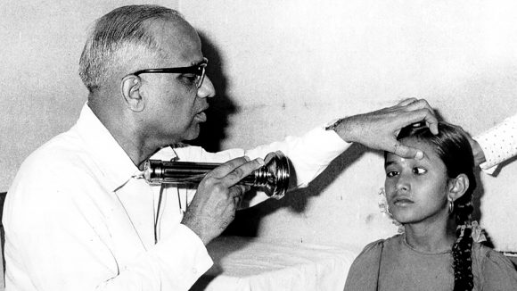 En lege undersøker øynene til en jente i India på 1950-tallet.