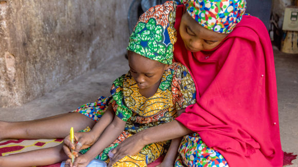 A mother helps her daughter with some school work.