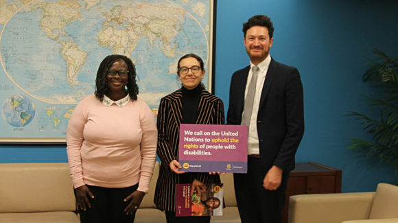 Sightsavers-ansatte i FN holder skilt som sier 'Vi ber FN om å opprettholde rettighetene til mennesker med nedsatt funksjonsevne'.