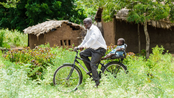 A man gives a young girl a ride on the back of his bicycle.