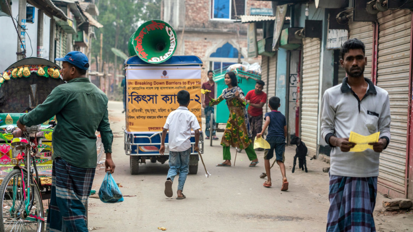En megafon-moped kjører gjennom en gate i Bangladesh.