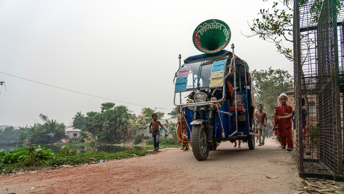 En megafon-moped kjører gjennom en gate i Bangladesh.