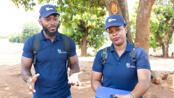 En mann og kvinne står utenfor før oppstarten av undersøkelser i forbindelse med kartlegging av elveblindhet.