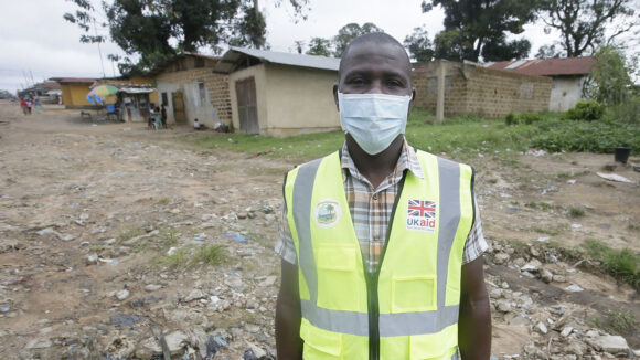 En mann står for et portrett mens han har på seg en maske.