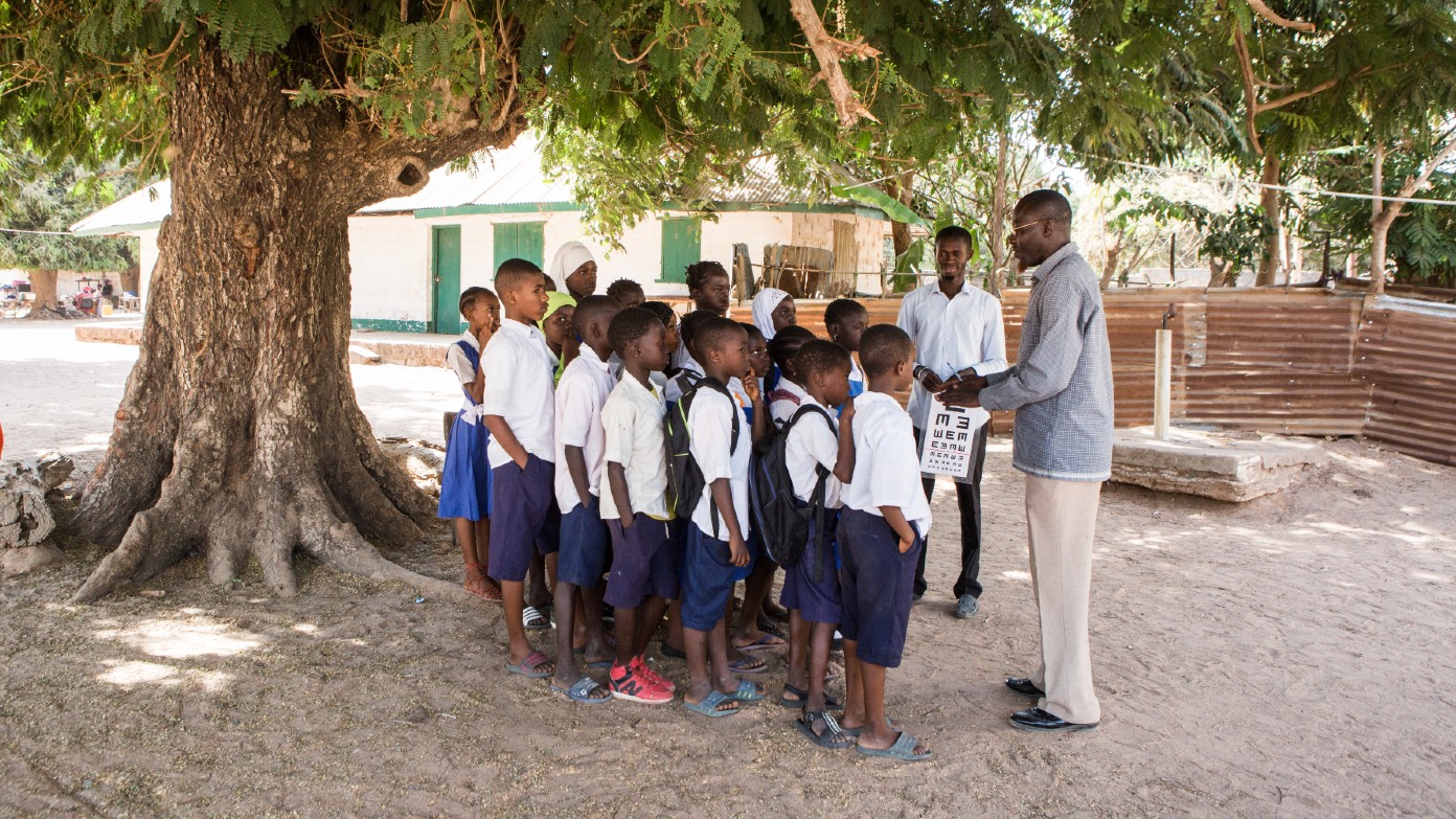 A man stands outside with a group of schoolchildren.