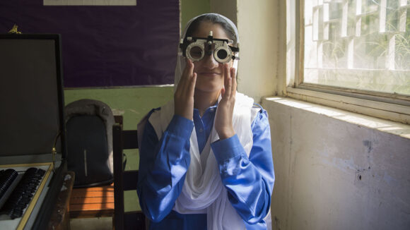 A girl smiles as she has her eyes tested.