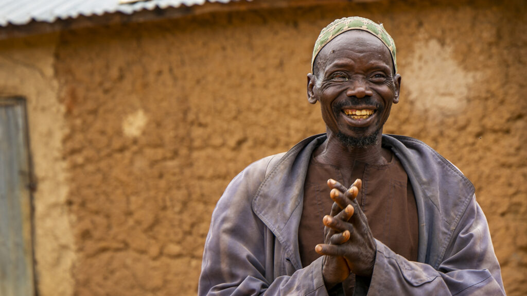 Adou smiler utenfor hjemmet sitt.