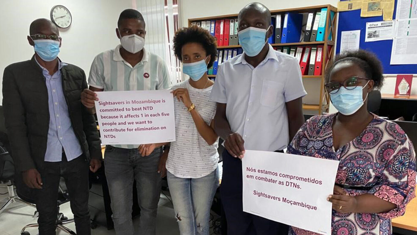 Fem ansatte fra Sightsavers poserer for et foto med plakater som viser deres forpliktelse til å bekjempe NTDer.