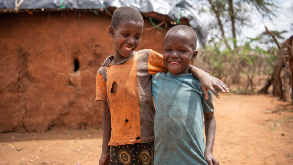 Naomi og Rakonin, to unge jenter, sto utendørs. Smilende, med armene rundt hverandres skuldre.