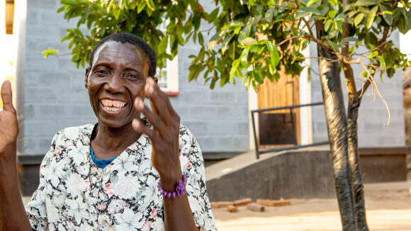 Vainesi smiler og klapper utenfor hjemmet sitt i Malawi.