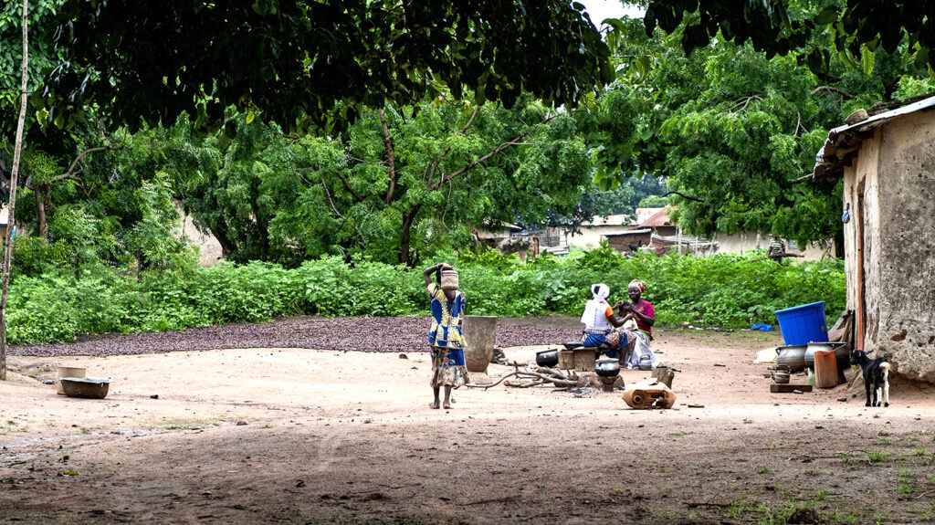 En landlig landsby i Benin, med støvete veier og frodig vegetasjon i bakgrunnen.