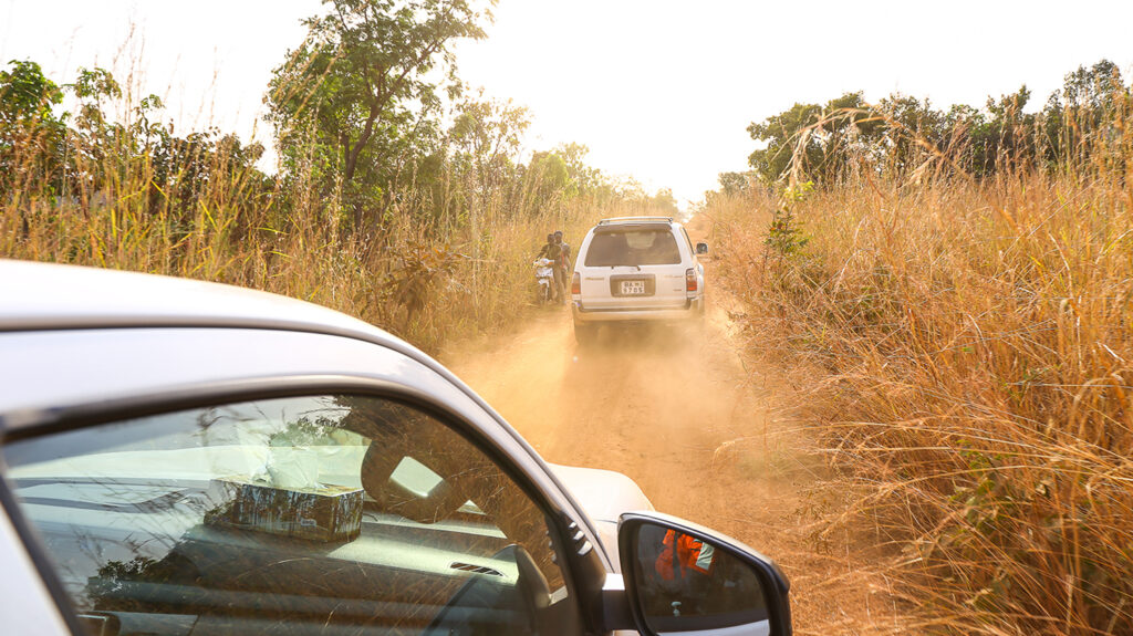 Lastebiler kjører på en støvete veibane i Benin.