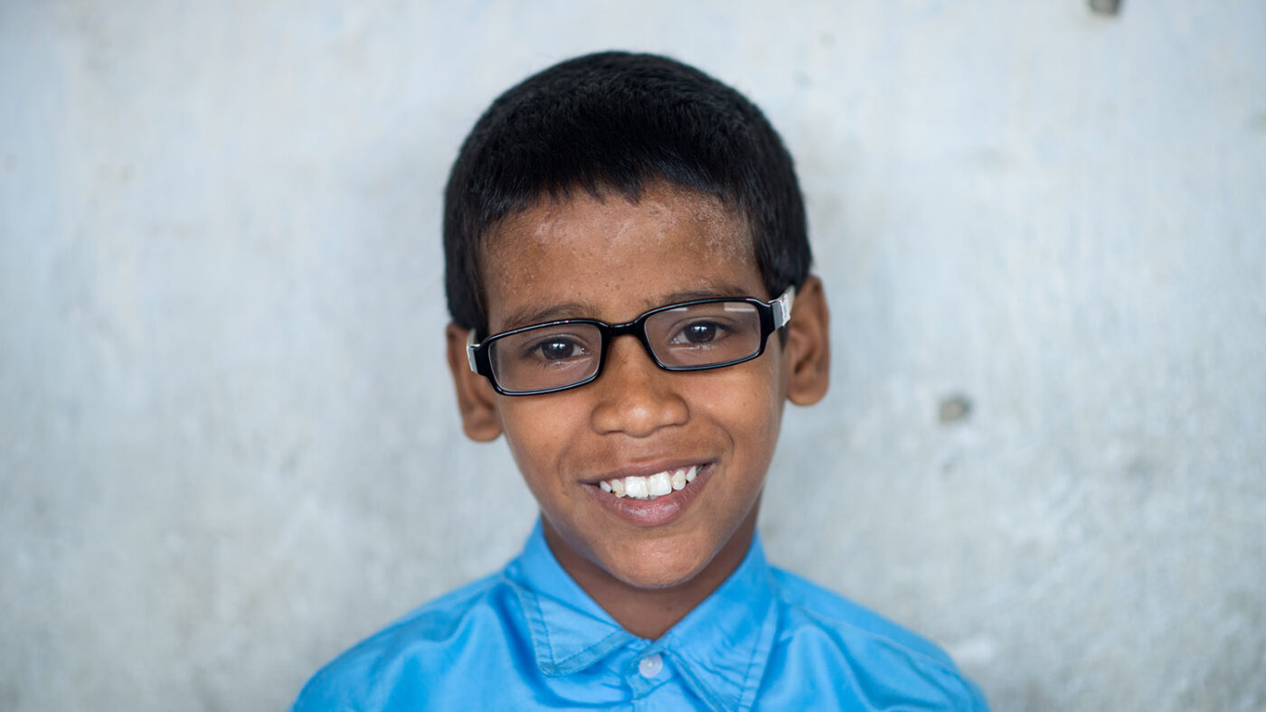 Shahid smiler for et portrett med brillene.