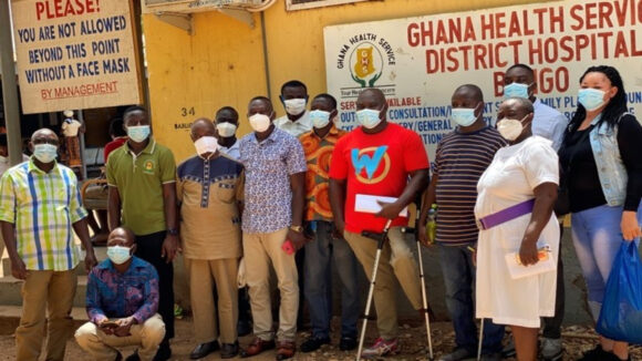 En gruppe mennesker med ansiktsmasker står utenfor et sykehus i Bongo, Ghana.