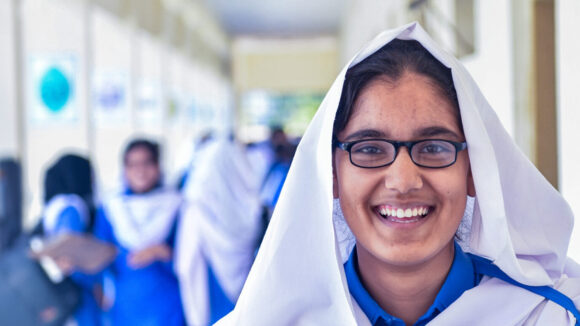 Skolejenta Zahra smiler mens hun har på seg de nye brillene.