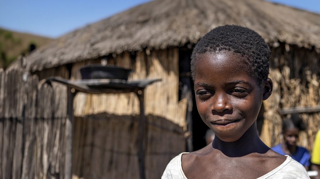 En liten jente smiler og ser i det fjerne.