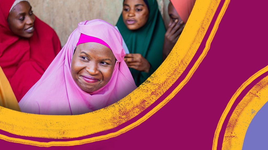 En kvinne iført en chador (tradisjonell kappe) smiler mens hun ser bort fra kameraet.