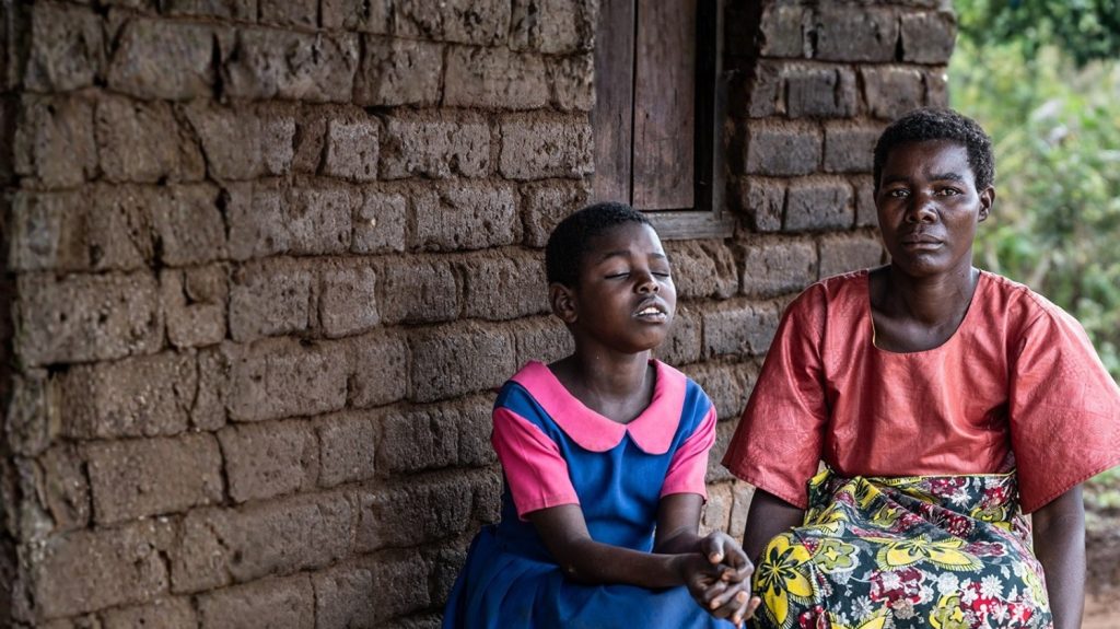 Melia og Veronica sitter utenfor hjemmet sitt i Malawi.